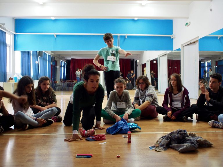 Dr. Myrto Pigou-Repousi leading a drama activity with youth sitting in a circle around her