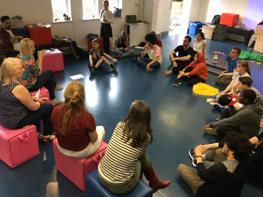 Students sitting on the floor in a circle with their teacher in Coventry, England
