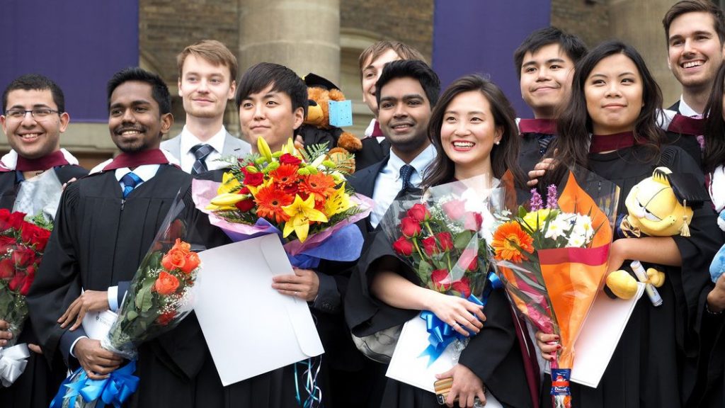 Graduates from the University of Toronto standing together in front of Convocation Hall