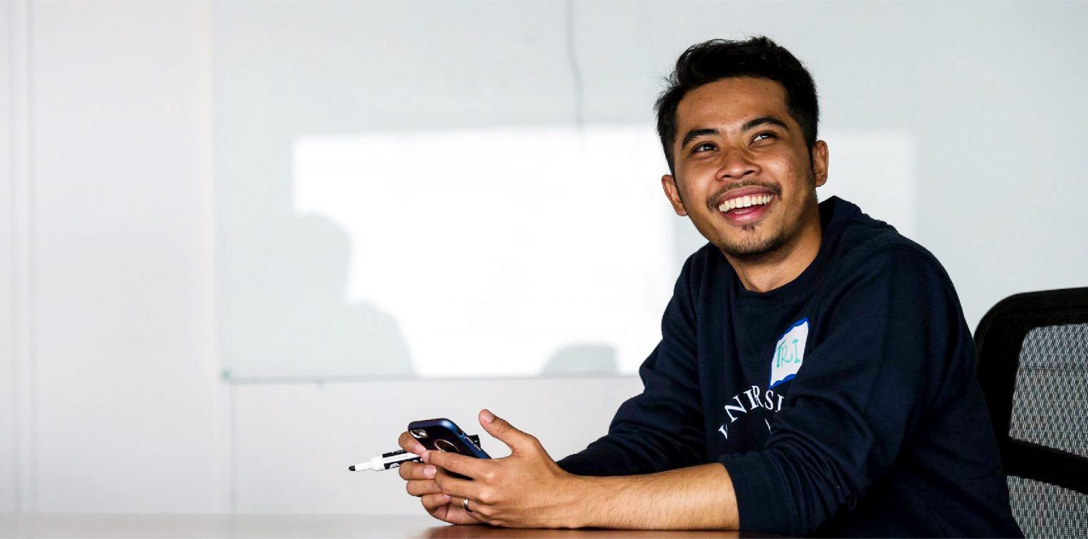 A student smiling and holding a cellphone.