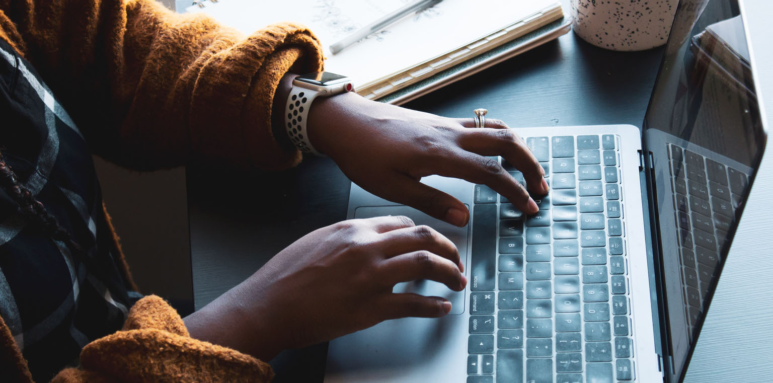 A person typing on a laptop keyboard.