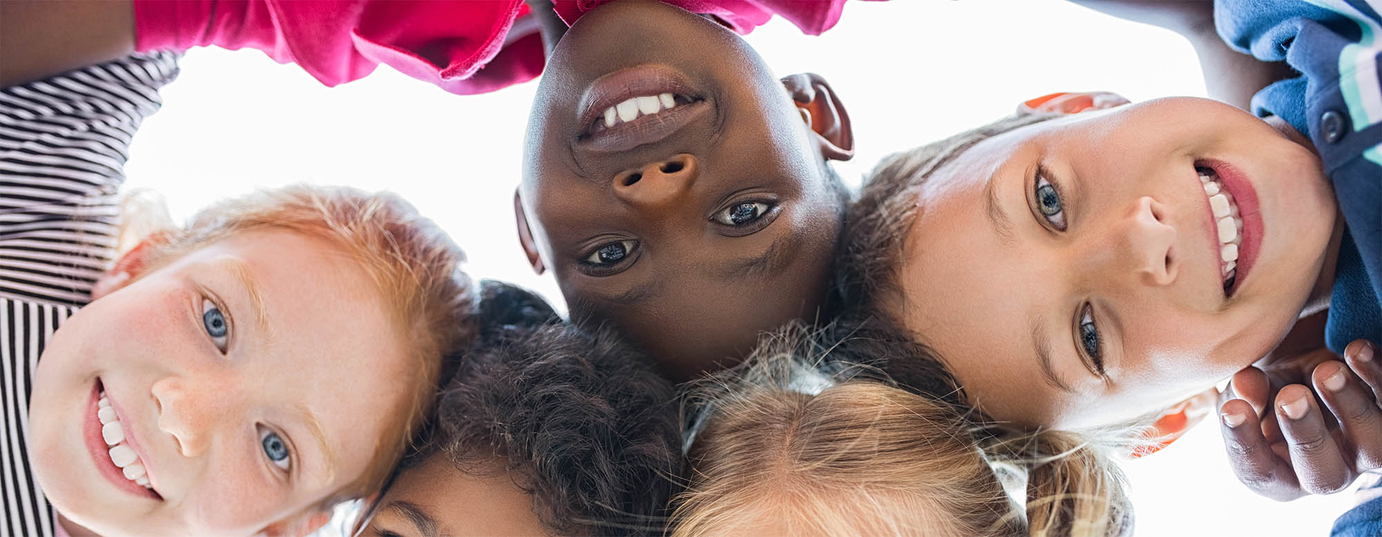Children smiling and looking directly into a camera. 