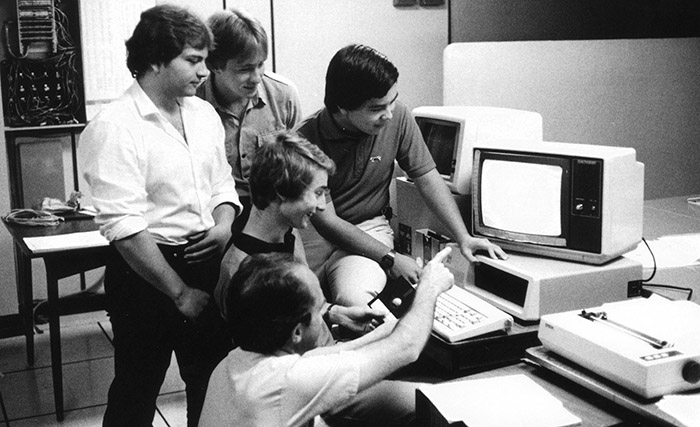 Five people standing by a computer - Archive photo.