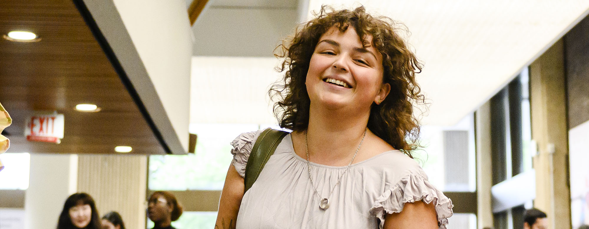 A student smiling and walking in OISE's library.