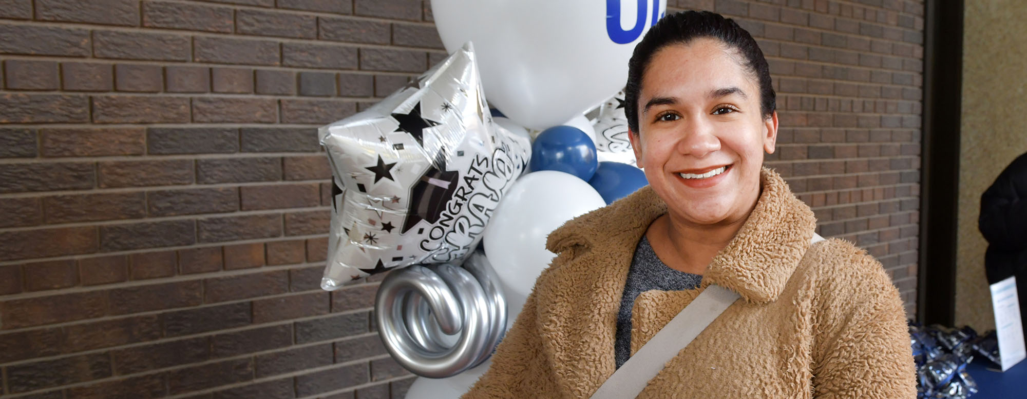An OISE graduate standing by some balloons at OISE Swag Day.