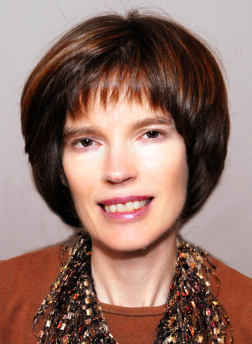 Woman with short brown hair, dark orange shirt, and dark accent scarf