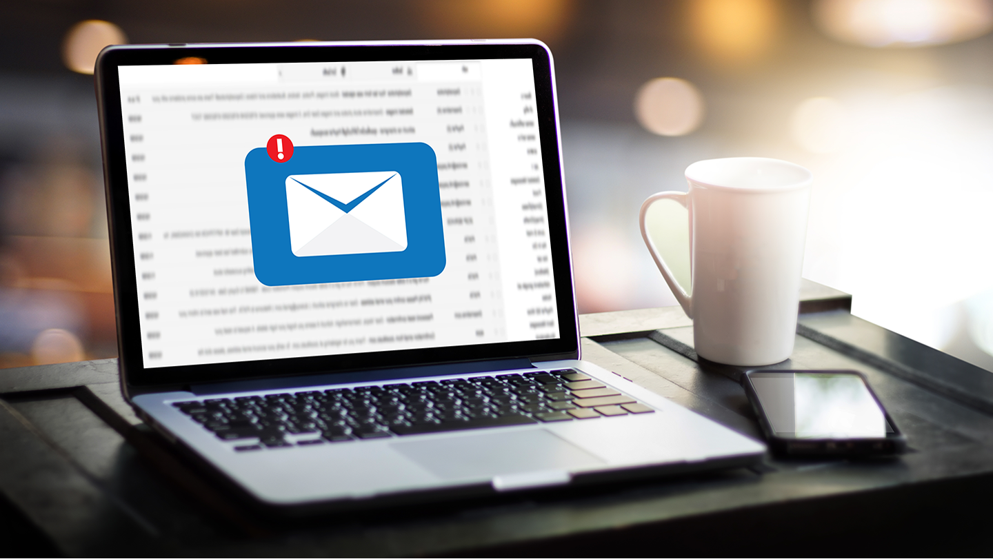 An open laptop on a desk, showing an email application. A pop-up is shown, a white envelope on a blue background, with a red ex