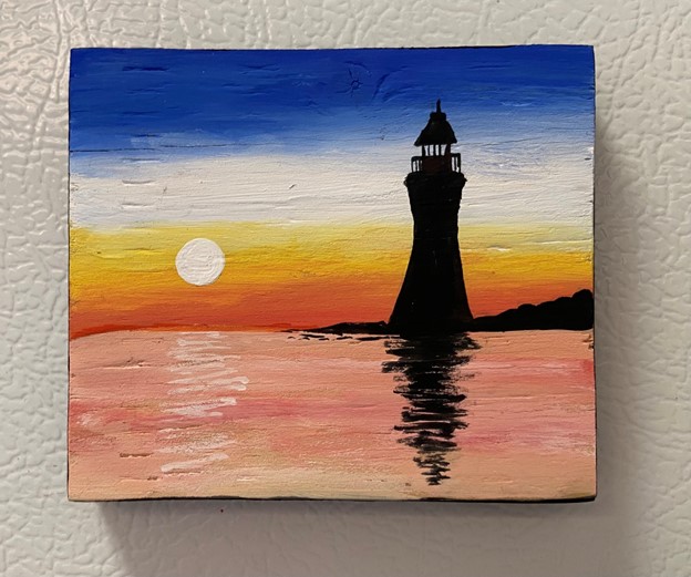 Silhouette image of a lighthouse reflected in water against the setting sun