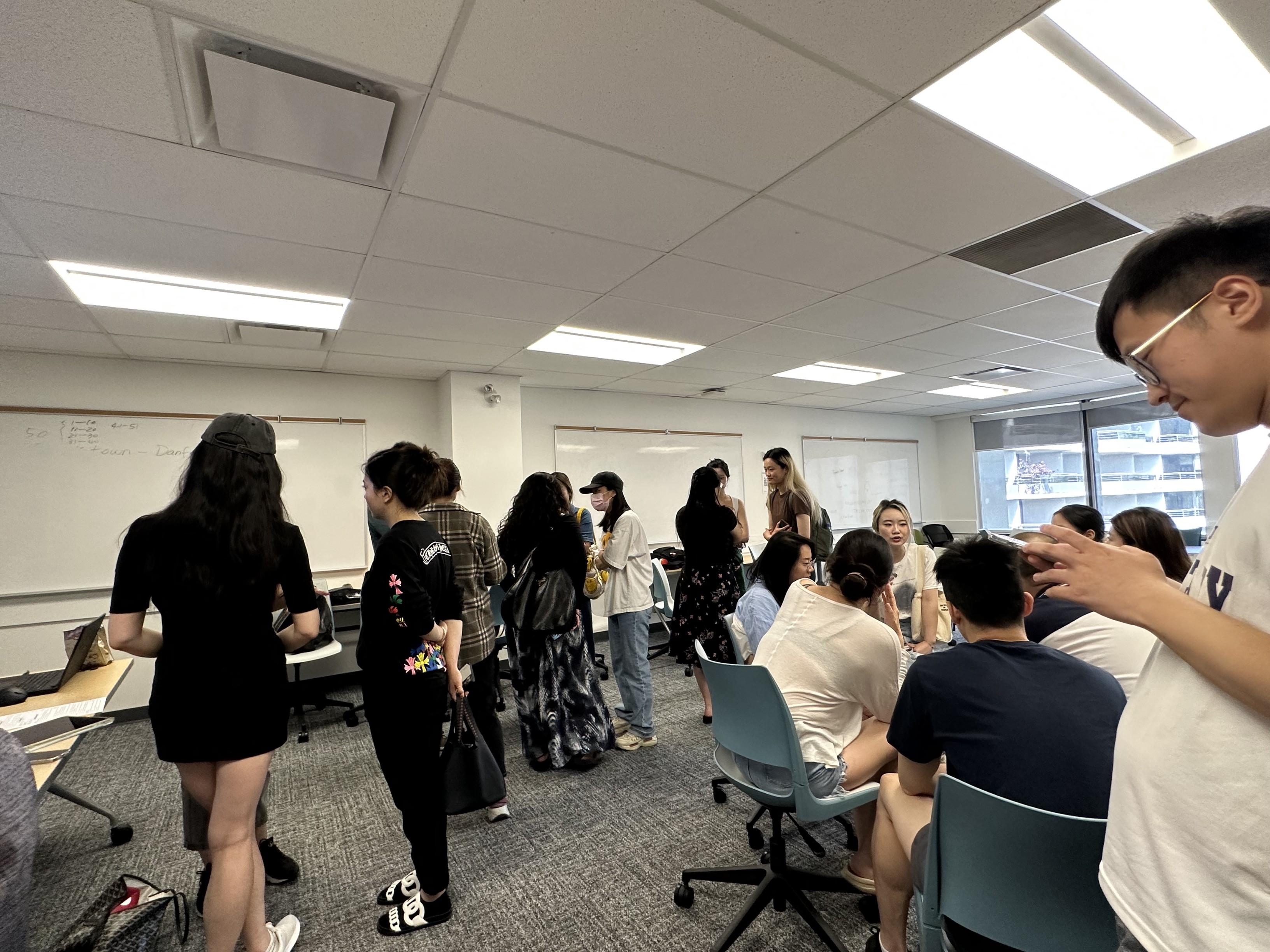 A gathering of people standing and sitting in small groups and chatting
