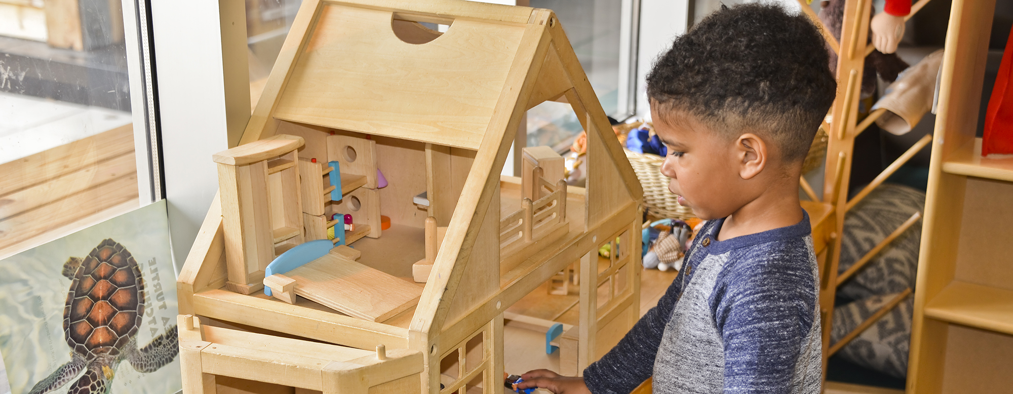 A child playing with figures in a wooden house.