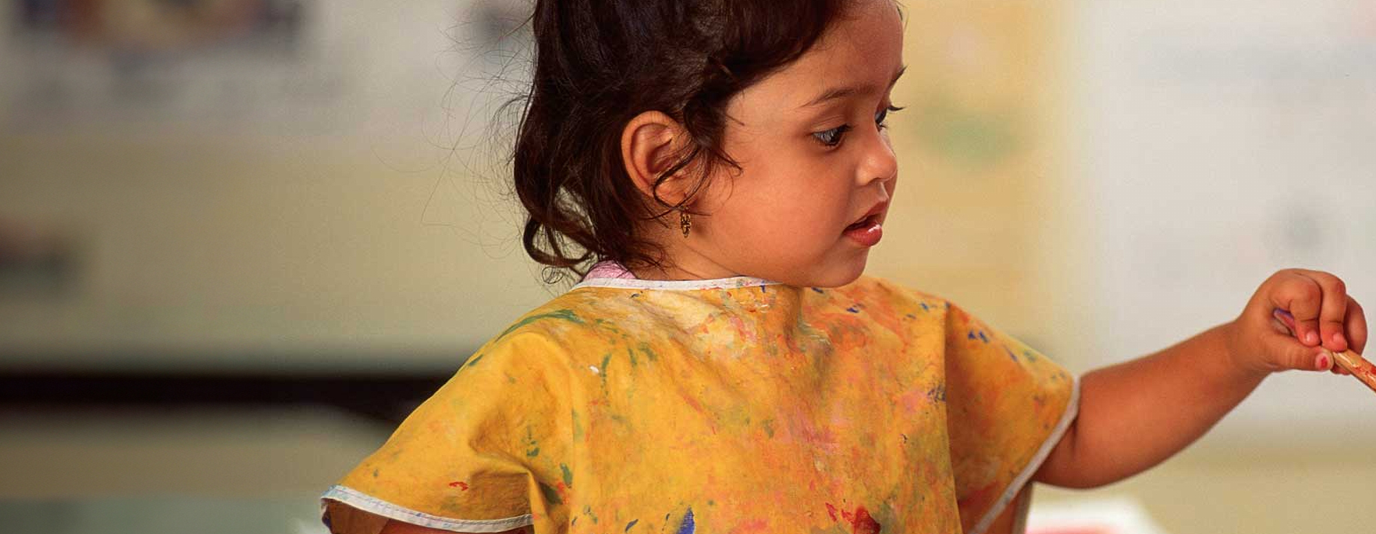 A child painting and wearing a painter's apron. 