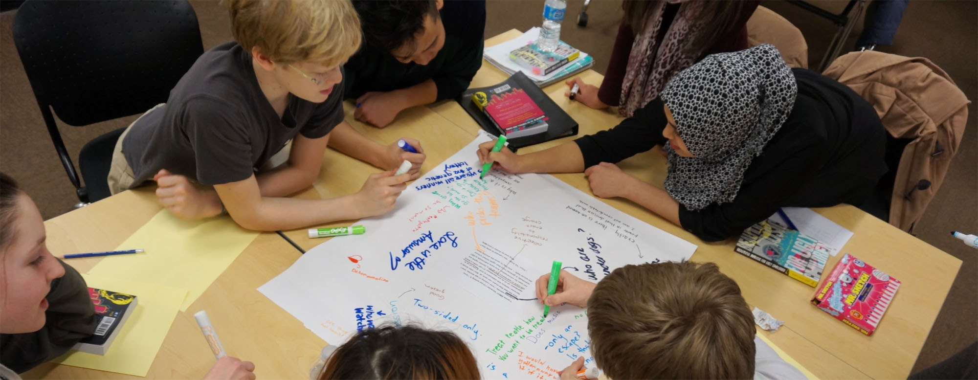A group of students writing on a piece of paper.