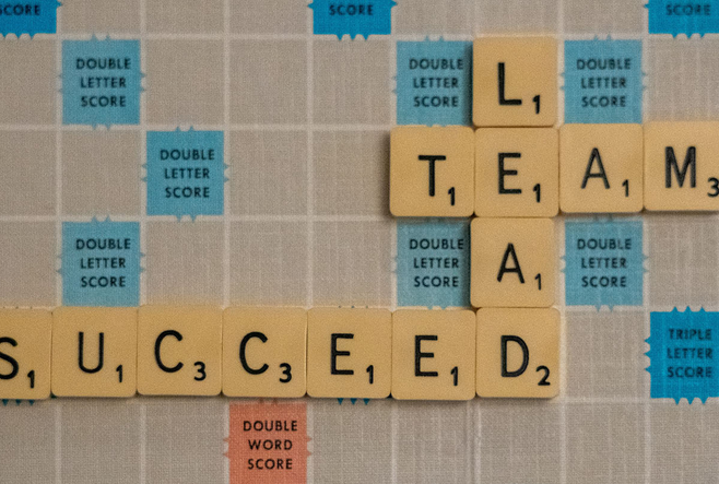A Scrabble board with the connecting words: Lead, Team, and Succeed. 