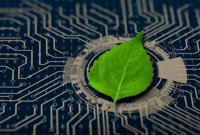 A bright green leaf lies on a blue-and-silver circuit board, symbolizing green technology.