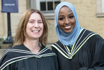 Two students smiling at OISE convocation. 