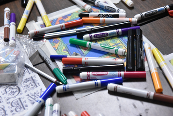 a profusion of markers and papers jumbled on a table top