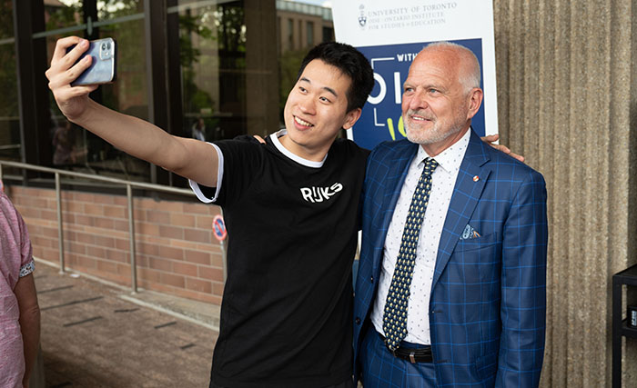 An OISE graduate taking a selfie with Normand Labrie.