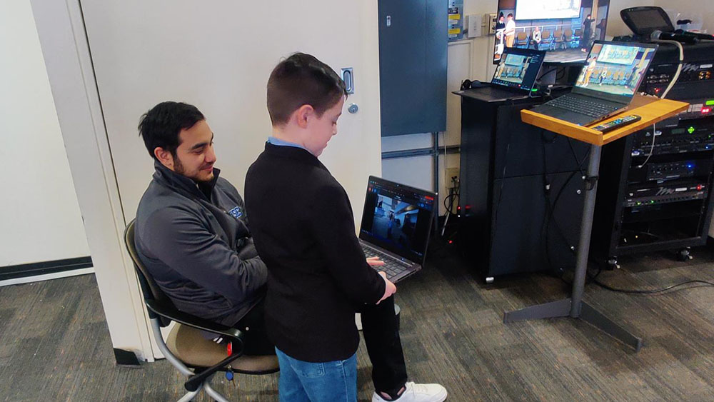 Education Commons team member, Daniel, showing a child the technology being used for the TechDudes event.