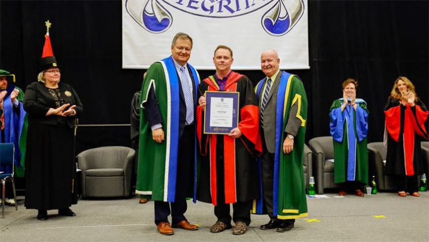 OISE alum Glen Sharpe, centre, receiving an award.