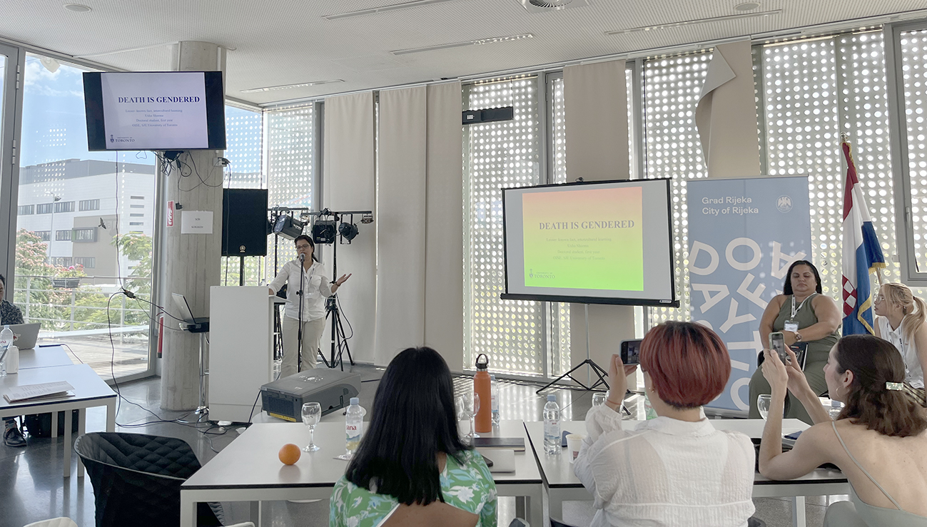 A South Asian student is speaking at a podium in front of an audience