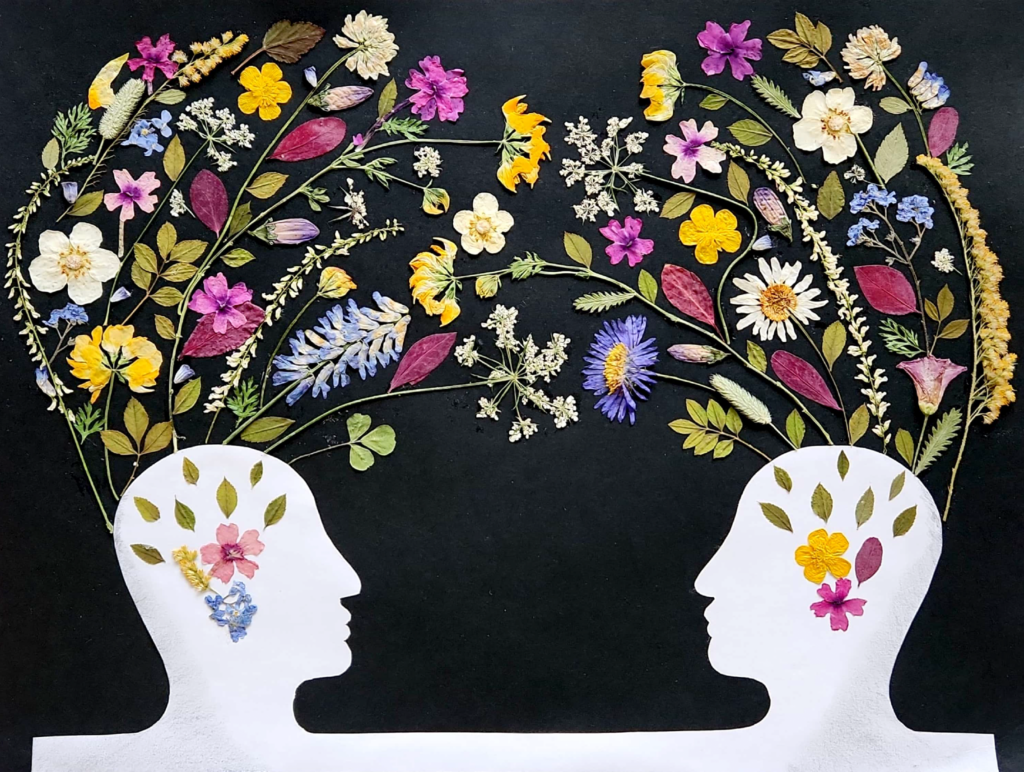 Two silhouttes looking at the each other, with real flowers connecting them.