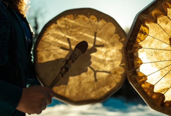 Two people hitting a drum.