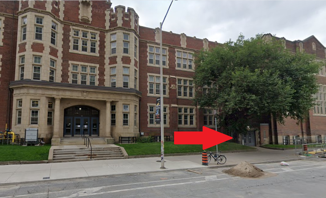 Photo of the front of a building with an arrow pointed toward an entrance on the right.