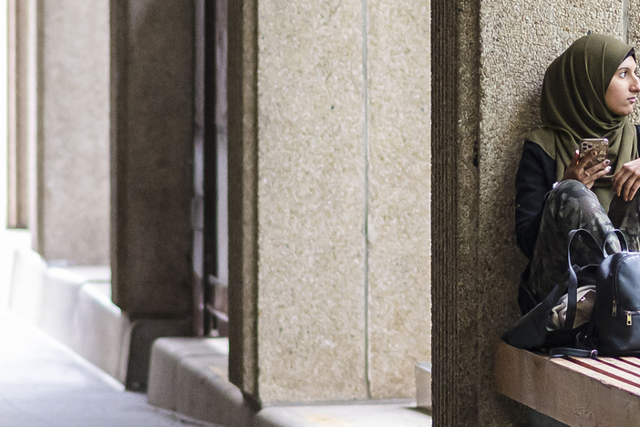 A student sitting outside the OISE building on a bench.