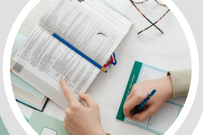 hands turning page of open book and writing on note pad eye glasses