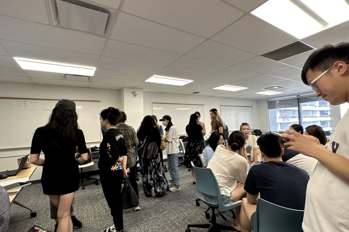 A gathering of people standing and sitting in small groups and chatting