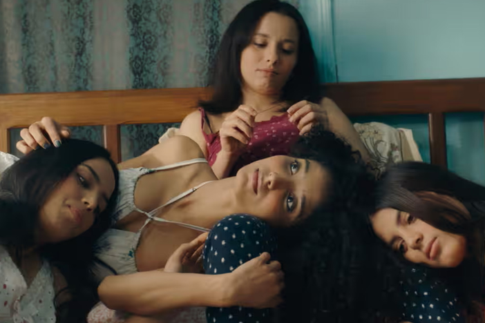 Four sisters with dark brown hair are sitting in a bed together