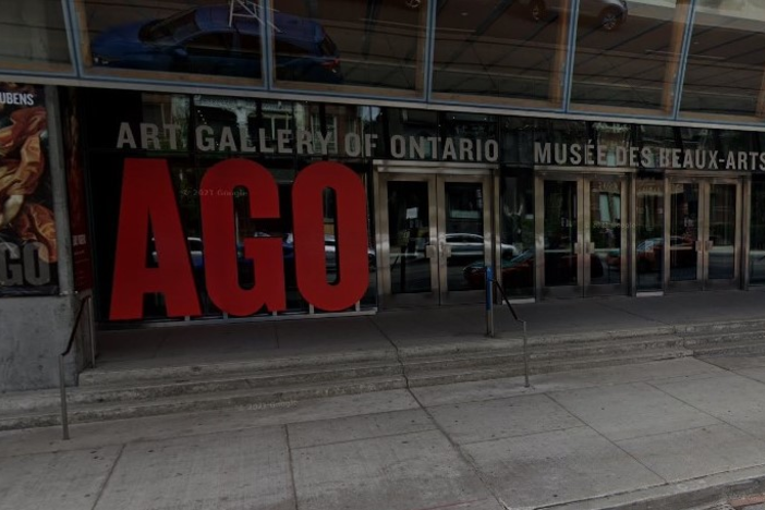 urban street and glass doors at front of building with large sign with letters A G O
