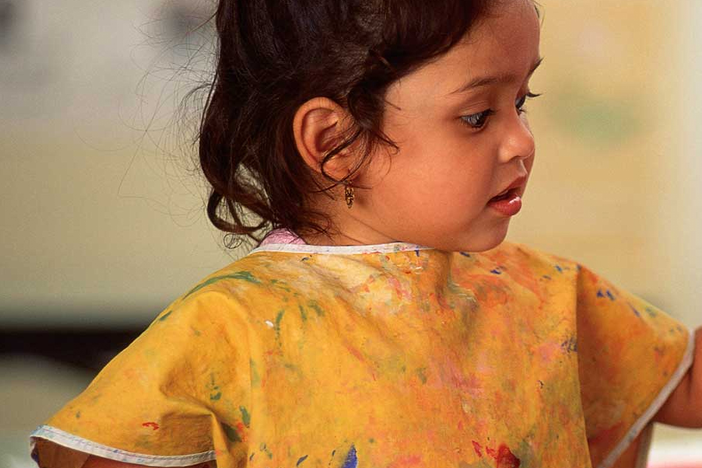 A child painting and wearing a painter's apron.