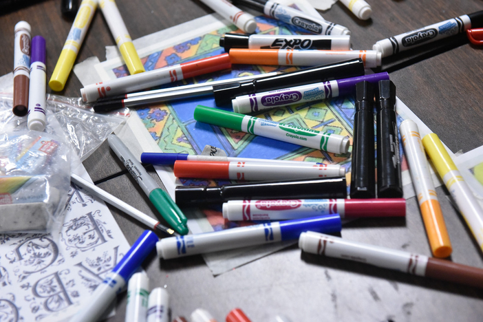 a profusion of markers and papers jumbled on a table top