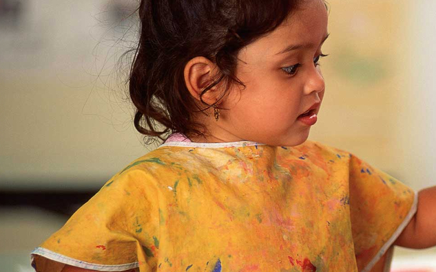 A child painting and wearing a painter's apron.