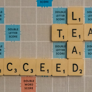 A Scrabble board with the connecting words: Lead, Team, and Succeed. 