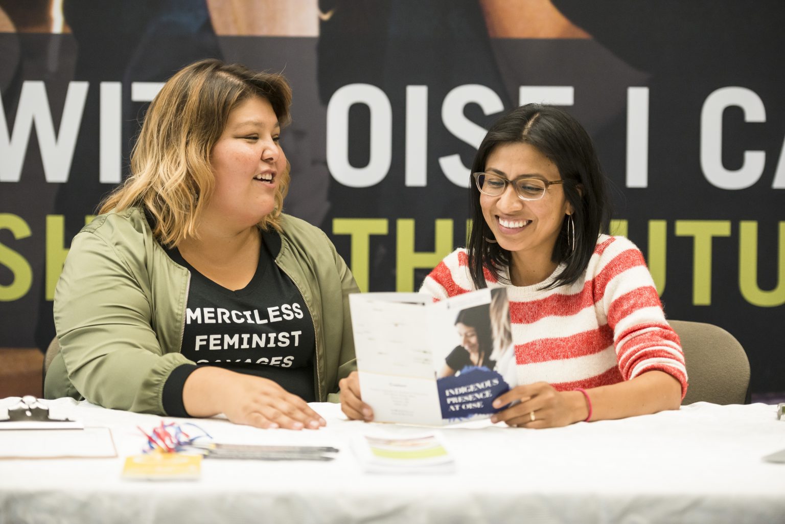 Image of two students sitting at a table in front of an OISE poster.