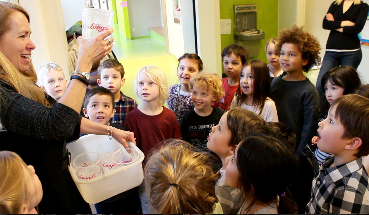 Zoe Donauhue standing with cups of water with her class of students