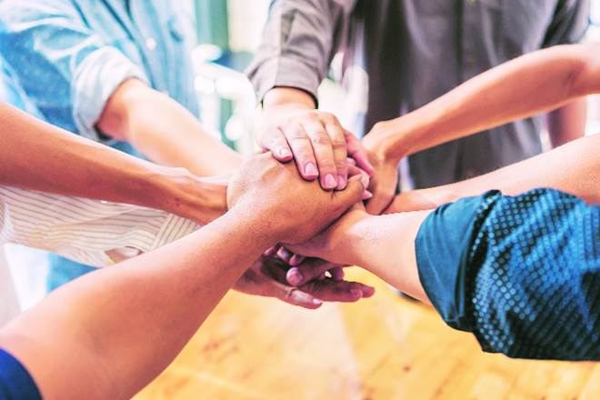 Team members joining hands in a stack during a meeting or team-building session, emphasizing cooperation and mutual support.a