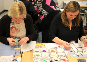 Two people sitting at a table working on an arts and crafts project.