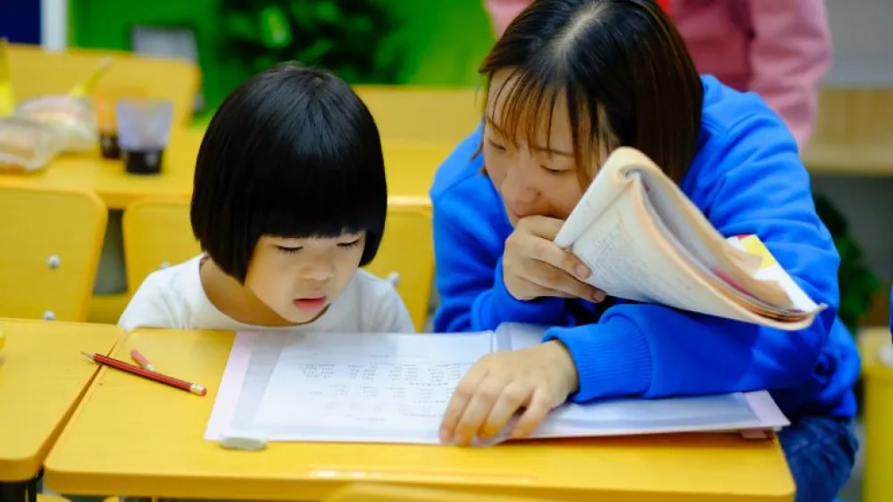 An instructor helping a child read.