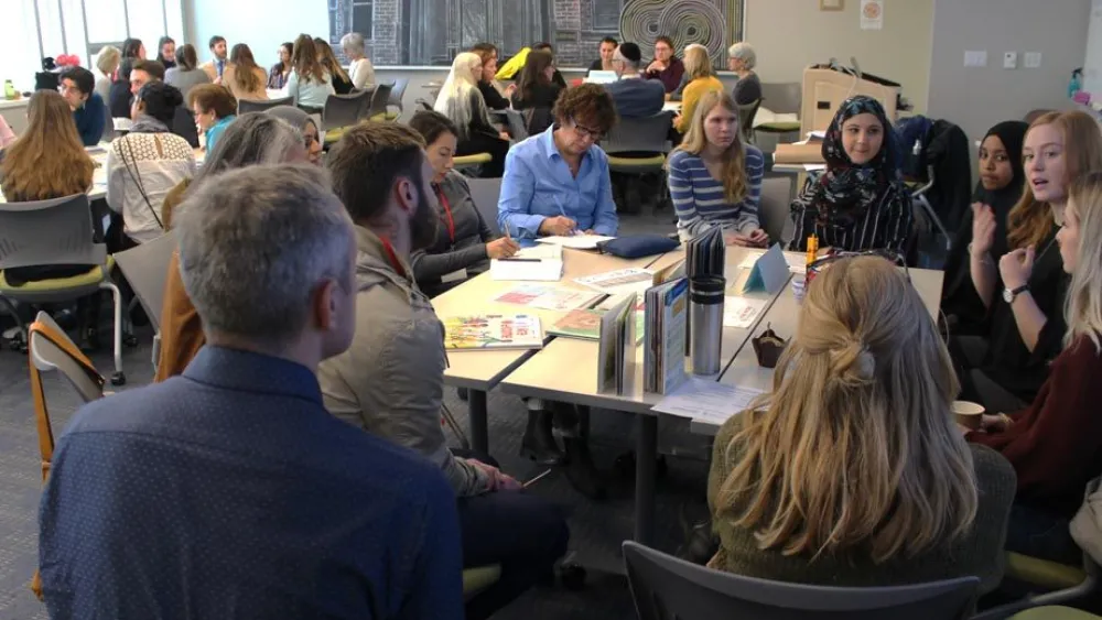 A group of people seated around tables in a room, engaged in discussions or activities.