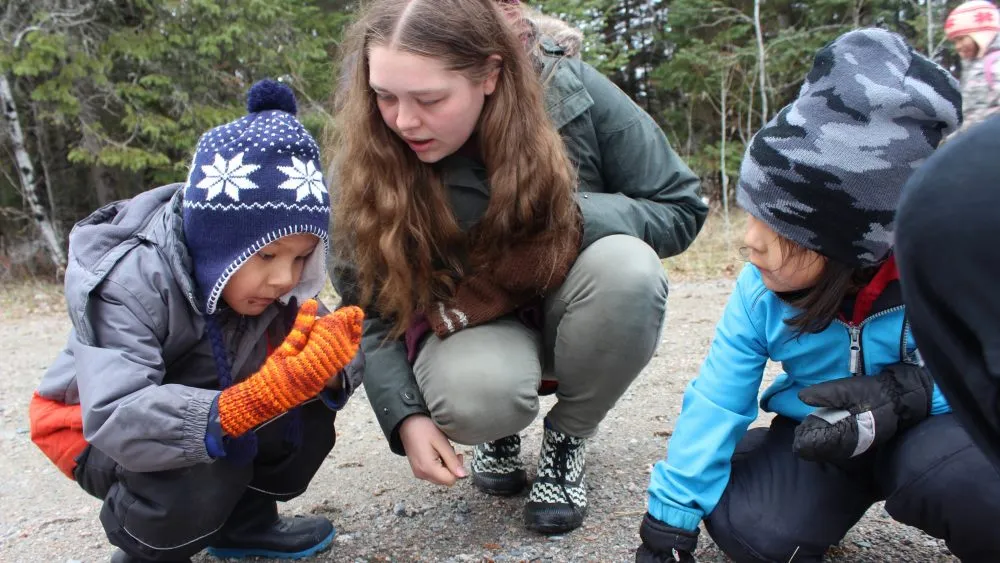 Two children and an adult looking at rocks.