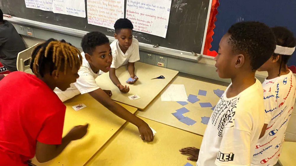 Children playing a playing card game on a desk.