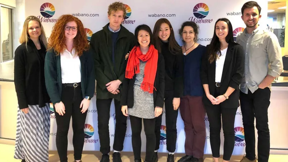 A group of people standing in front of a step and repeat banner.