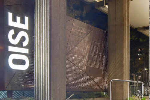 OISE entrance sign illuminating at night.