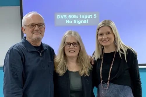 Dr. Kathleen Gallagher, Dr. Rachel Turner-King and Professor Jonothon Neelands posing in front of a projector screen after a presentation