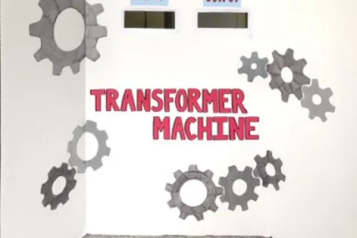 A large piece of paper with gear icons, two cutout slots and a title that reads, "Transformer Machine".
