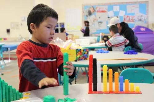 A child from Pegamigaabo School in Big Grassy First Nation lines up progressively taller multilink cube towers next to their corresponding number.