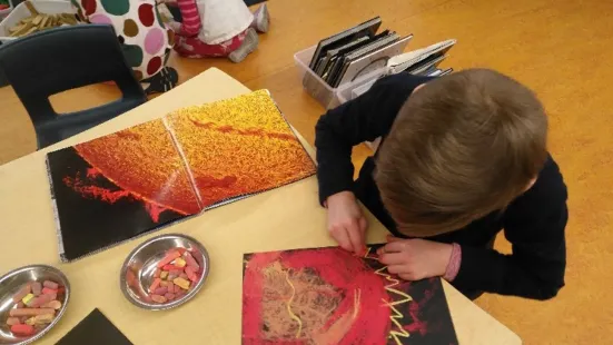 A kid seated at a table, drawing a sun
